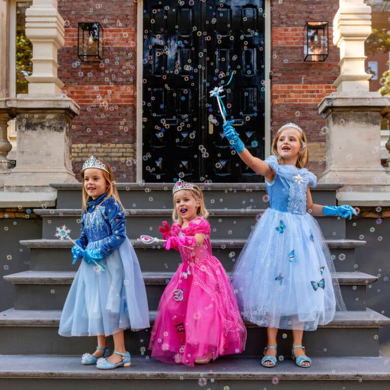 Meisjes dragen een blauwe Elsa jurk, een prinsessenjurk met tiara en handschoenen op de trap tussen zeepbellen